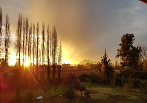 A landscape with a sunset, trees, and a mountain in the background. - Hotel El Almendro (Buin)