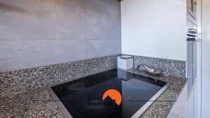 Een moderne keuken met een zwart inductiekookplaatje, granieten aanrecht en een roestvrijstalen spoelbak.