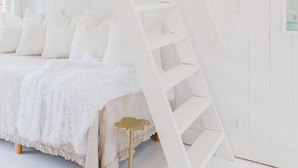 A white bedroom with a bed, a white ladder, and a white wall. - Beach chic guest cottage, in town, just renovated (Nantucket)