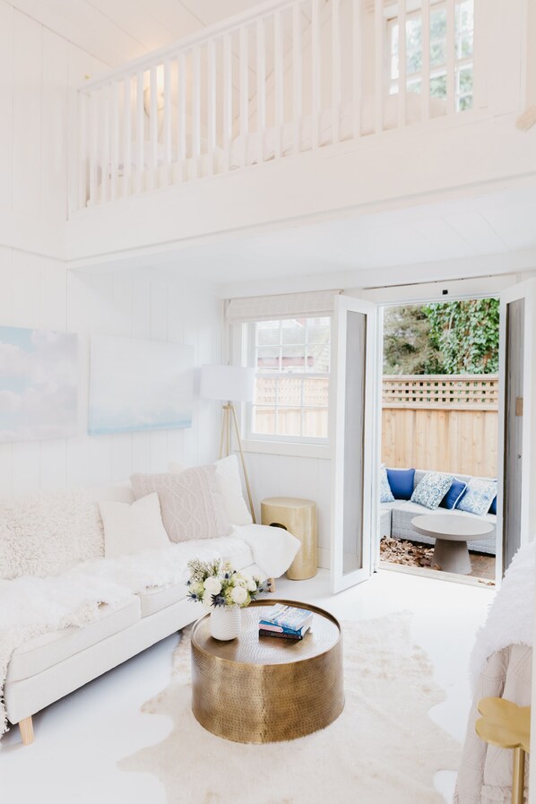 Relax in this stylish living area with a balcony, sofa, and coffee table, offering a peaceful view of the surrounding greenery.