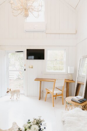 Enjoy a spacious room with a high ceiling, wooden desk, and large window offering a view of the outdoor area.