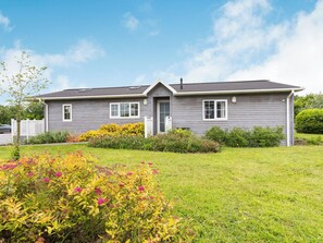 A two-story house with a front porch, a garage, and a well-maintained garden with various flowering plants.