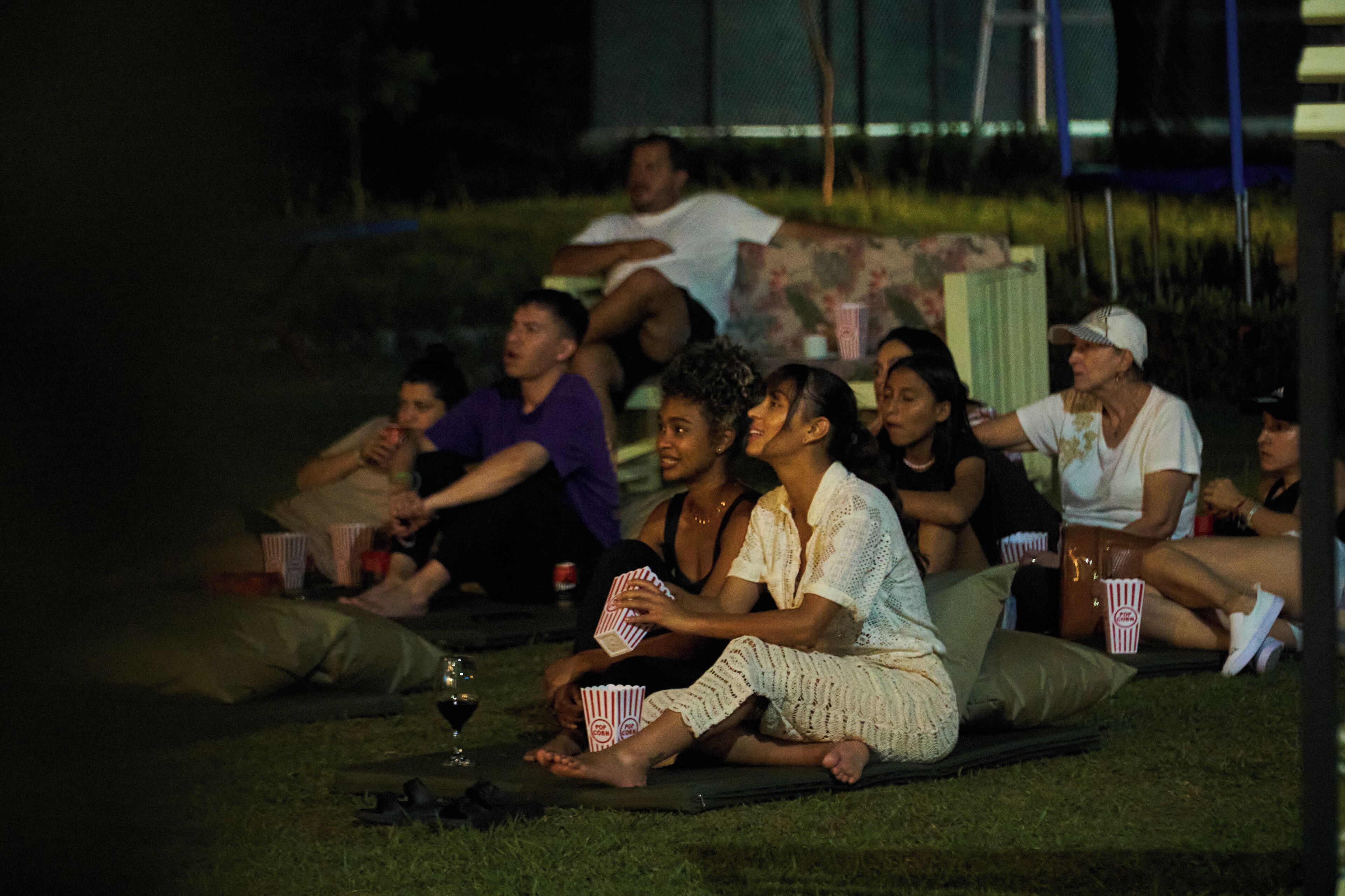 A group of people sitting on the grass outdoors at night.