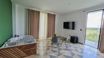 Un baño moderno con una bañera independiente, una mesita con una planta y una silla.