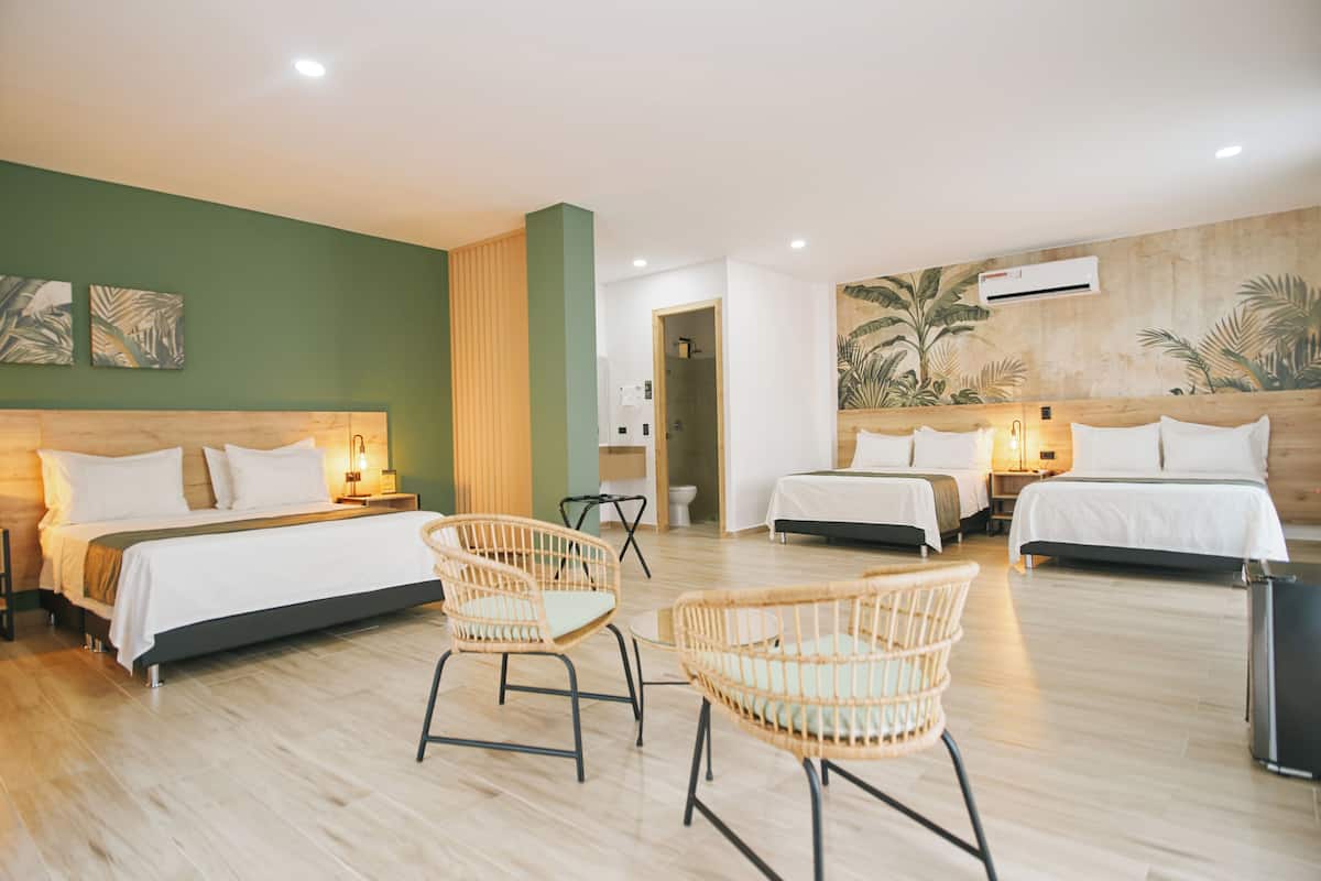A hotel room with two beds, wicker chairs, a wooden floor, and a mural on the wall.