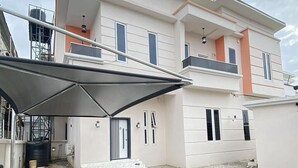 A modern two-story house with a covered patio area. - Pearl luxury 4 bedroom home (Lagos)