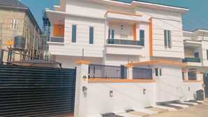 A modern two-story house with a balcony, a gated entrance, and a clear sky. - Pearl luxury 4 bedroom home (Lagos)