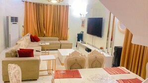 A living room with a sofa, a coffee table, a TV, and a dining table with chairs. - Pearl luxury 4 bedroom home (Lagos)