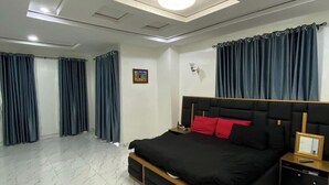A modern bedroom with a large bed, a nightstand, a wall-mounted light, and a ceiling light. - Pearl luxury 4 bedroom home (Lagos)