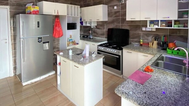 A modern kitchen with a central island, stainless steel appliances, and white cabinetry. - Pearl luxury 4 bedroom home (Lagos)