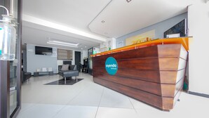 A reception area with a wooden reception desk, a seating area with a sofa, and a glass display case. - Vittapark (Medellín)