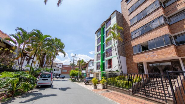 A hotel with a modern brick facade, a green vertical accent, and a gated entrance. - Vittapark (Medellín)