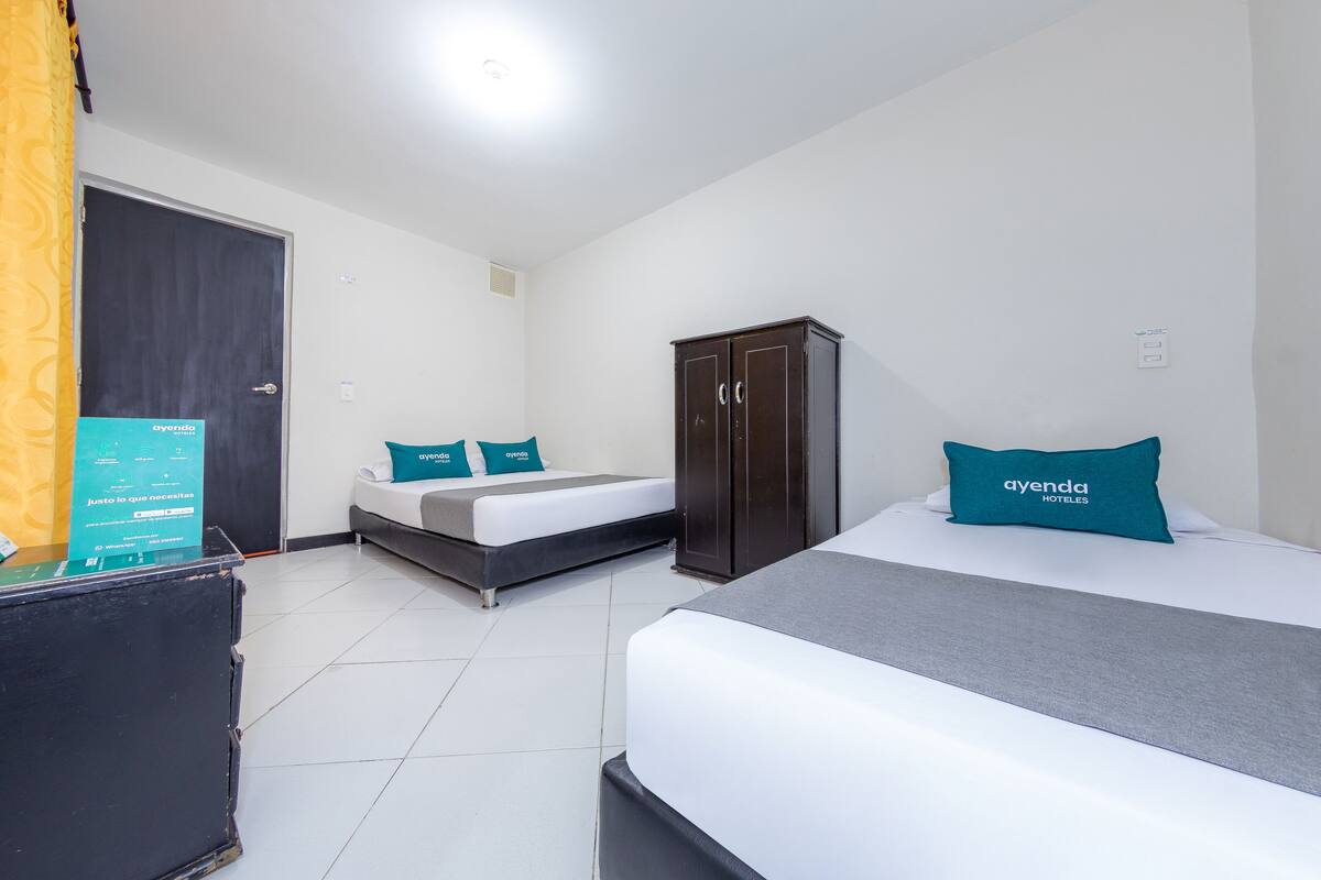 A hotel room with two beds, a wardrobe, and a desk with a computer.