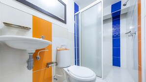 A bathroom with a white sink, toilet, and glass shower enclosure. - Vittapark (Medellín)