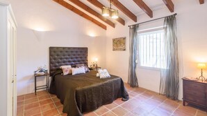 A bedroom with a large bed, a nightstand, a dresser, a window with curtains, and a map on the wall. - Las Ranas Cajiz by Ruralidays (Málaga)