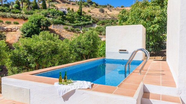 A swimming pool with a tiled edge, a metal ladder, and a white towel on the edge. - Las Ranas Cajiz by Ruralidays (Málaga)