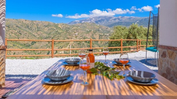 A wooden table set for dining with a scenic mountain view in the background. - Cinco Soles Árchez by Ruralidays (Málaga)
