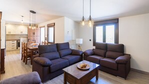A modern living room with two sofas, a coffee table, and a dining area with wooden furniture. - Cinco Soles Árchez by Ruralidays (Málaga)