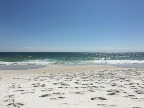 A beach with footprints in the sand and waves approaching the shore.