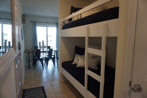 A bunk bed room with a dining area and a view of the city.