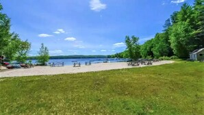 Un parque junto al lago con mesas de picnic y barcos.