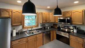 Una cocina moderna con armarios de madera, electrodomésticos de acero inoxidable e iluminación colgante.