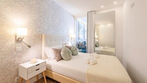 A modern bedroom with a large bed, bedside tables, a mirror, and a view of the outside. - GuestReady - Whole apartment in Lisbon (Lisboa)