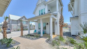 A two-story house with a porch, a covered patio, and a driveway. - Bright, modern home with shaded porch, AC & on-site golf, pool, beach access (Port Aransas)