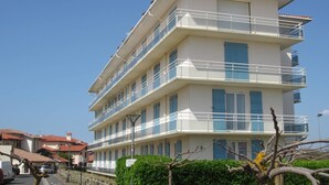 A multi-story hotel with balconies, a clear sky, and a sign indicating camping and vehicle parking. - HOSSEGOR. Central beach. Flat for 4 persons. Free Wifi. (SOORTS HOSSEGOR)