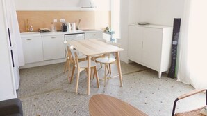 A modern kitchen with white cabinets, a wooden dining table, and a hanging light fixture. - HOSSEGOR. Central beach. Flat for 4 persons. Free Wifi. (SOORTS HOSSEGOR)