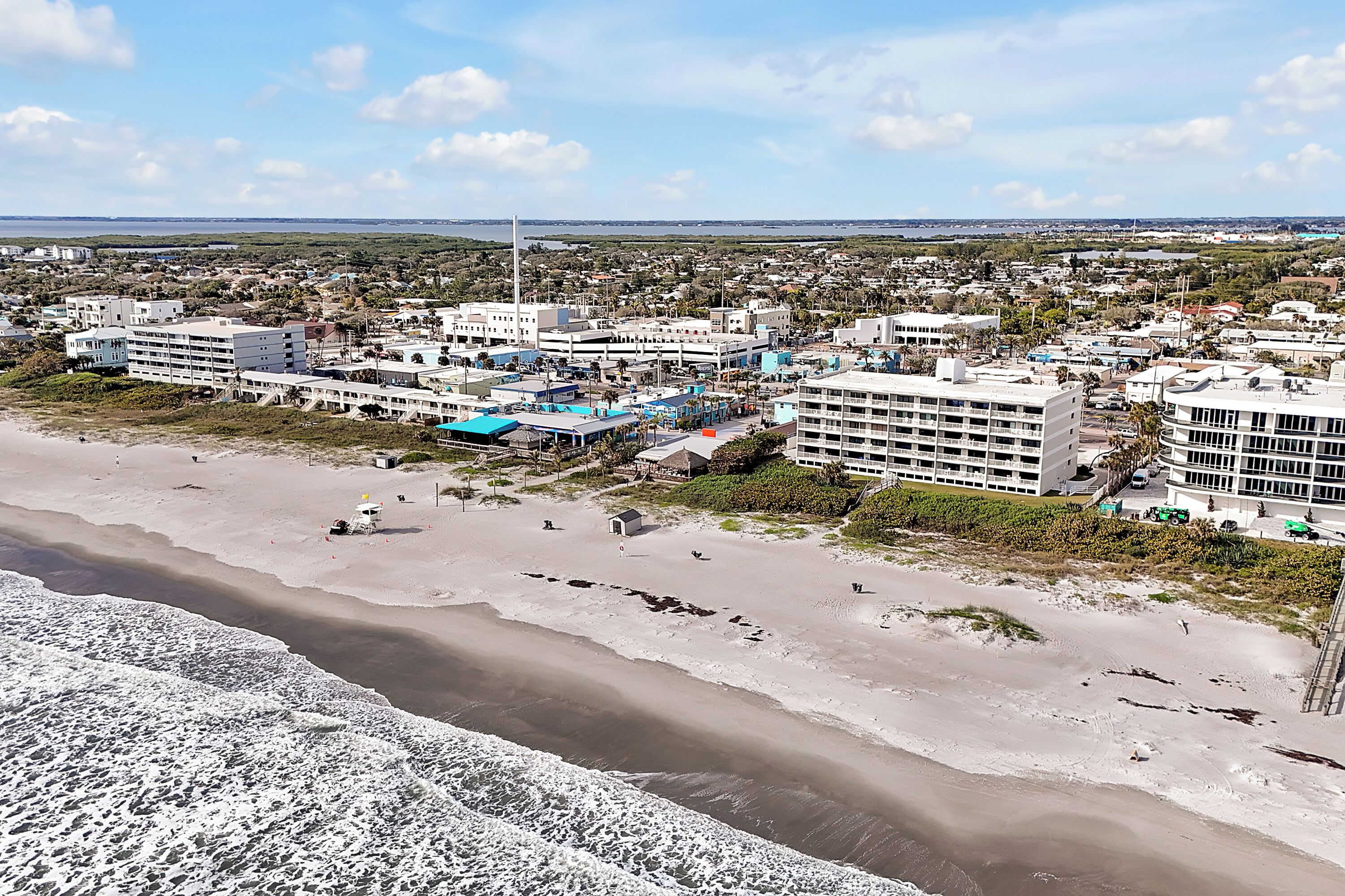 Ein Hotel an der Küste mit mehreren Gebäuden, einem Strand und Blick auf den Ozean.