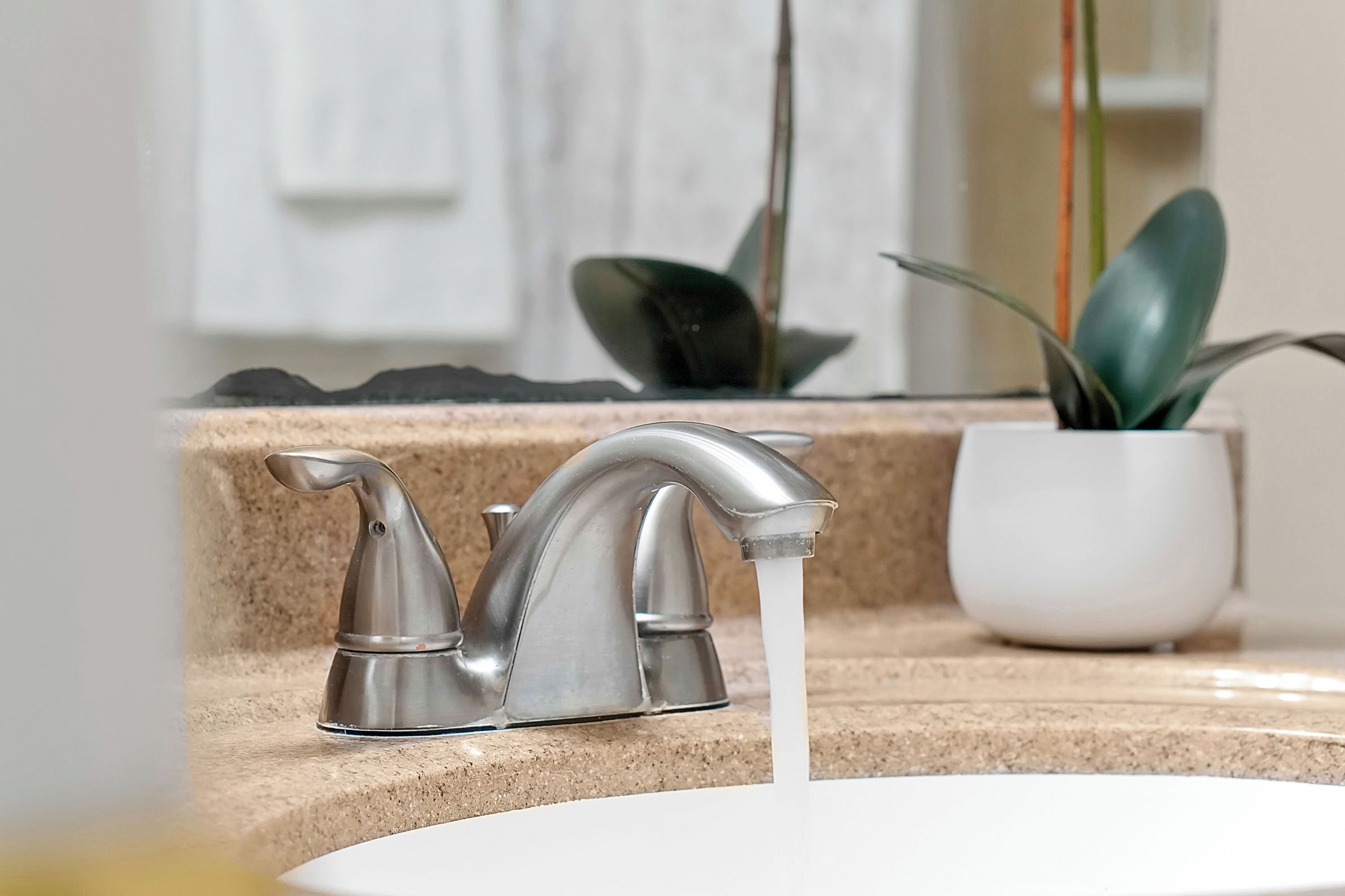 A bathroom sink with a modern faucet and running water.