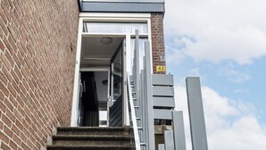 Ingresso di un edificio con muro in mattoni, cancello in metallo e cielo sereno.
