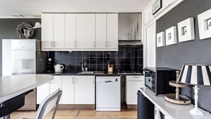 Una cucina moderna con mobili bianchi, un piano di lavoro nero, una lavastoviglie e un forno a microonde.