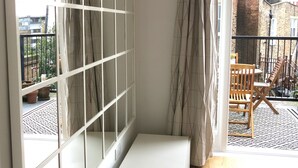 Une pièce dotée d’une grande fenêtre, d’un banc et donnant sur le balcon extérieur.