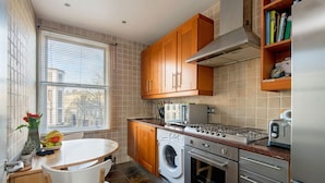 Une cuisine compacte avec des meubles en bois, un lave-linge encastré, une cuisinière et un réfrigérateur.