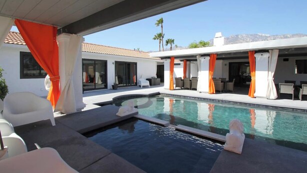A modern pool area with a clear view of a mountain in the background, a covered seating area, and a white building with large windows. - 4 Bedroom Modern Home, Pool+Spa+Guest House! (Palm Springs)