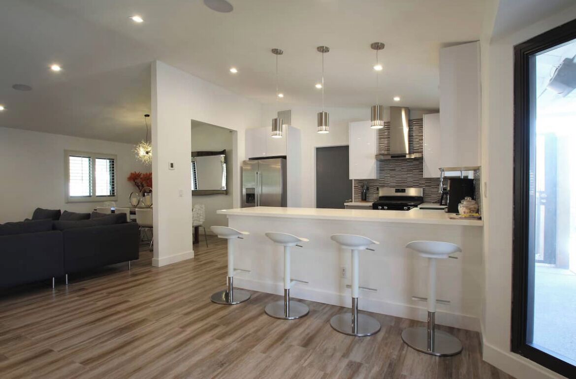 A modern kitchen with a central island, bar stools, and pendant lighting.