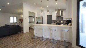 A modern kitchen with a central island, bar stools, and pendant lighting. - 4 Bedroom Modern Home, Pool+Spa+Guest House! (Palm Springs)