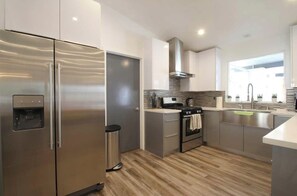 A modern kitchen with stainless steel appliances, a built-in oven, and a large window providing natural light.