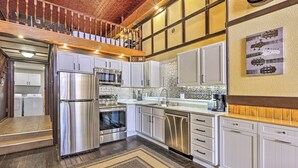 A modern kitchen with stainless steel appliances, white cabinetry, and a patterned backsplash.