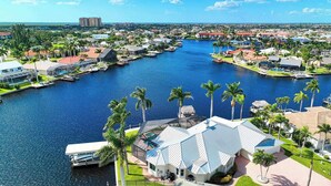 A waterfront property with a marina, palm trees, and a view of the cityscape. - VRCC Villa Jelly Key, a boaters dream in paradise (Cape Coral)