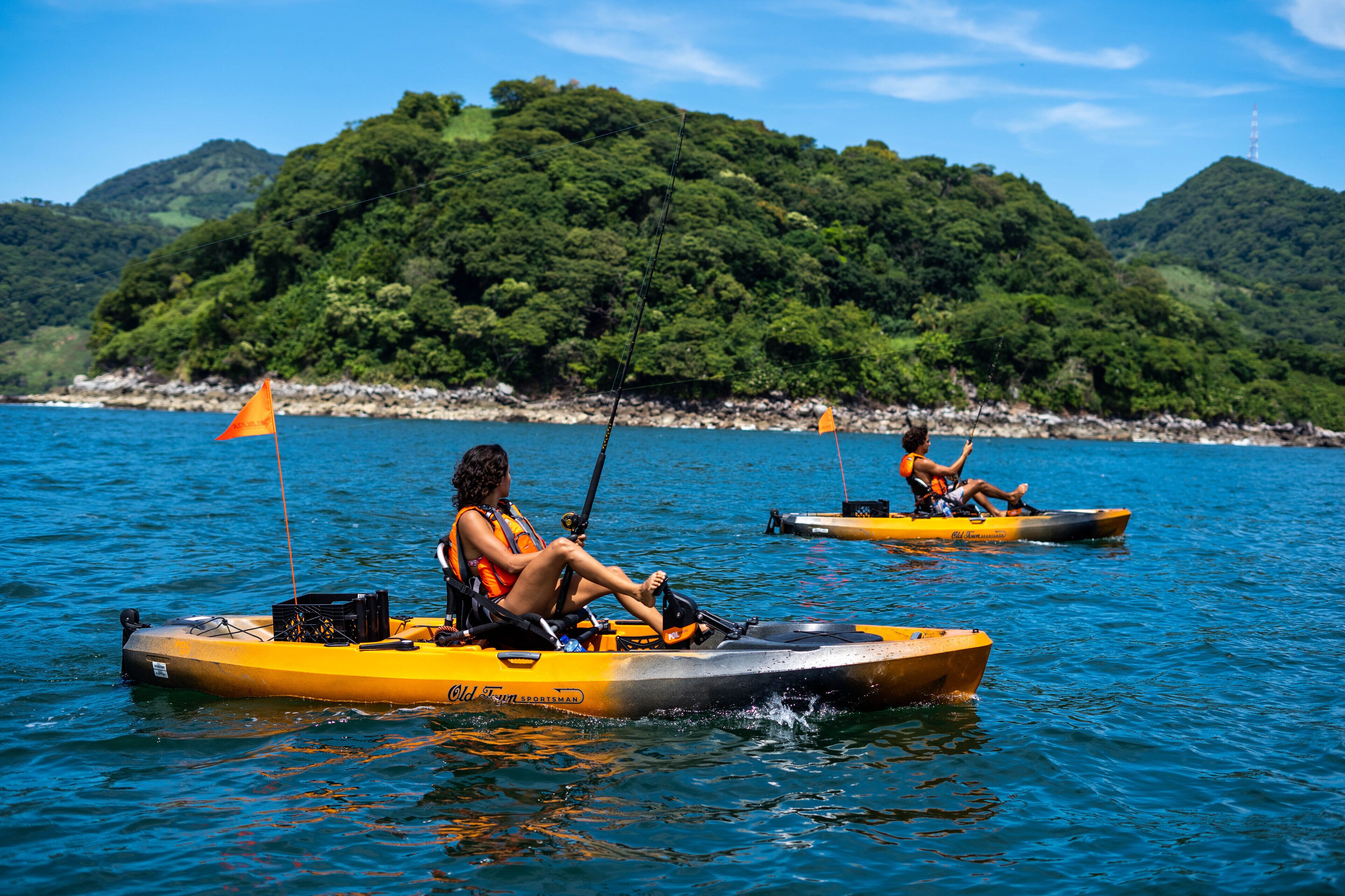 Dos kayaks sobre aguas tranquilas, con una colina boscosa al fondo.