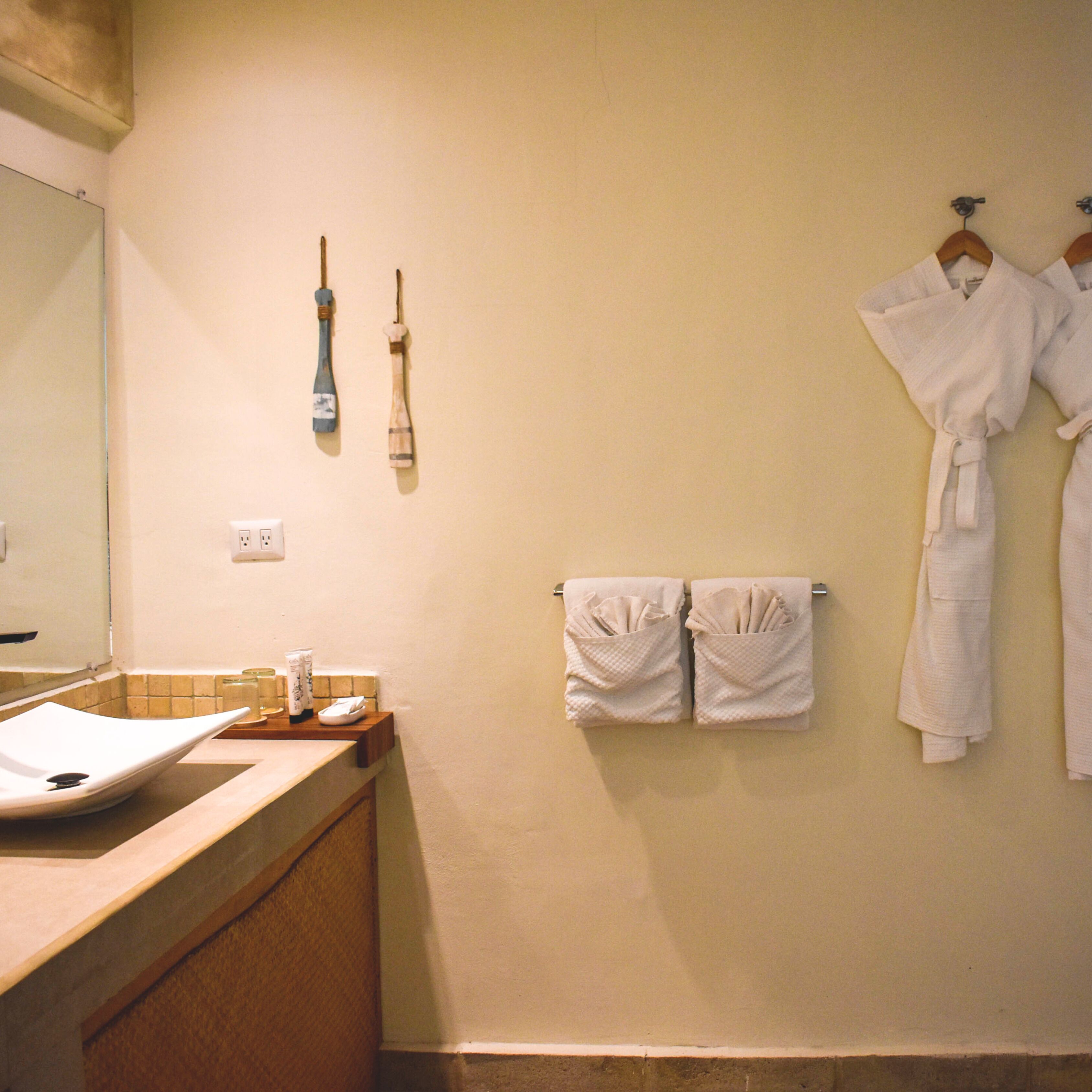 A bathroom with a sink, mirror, towel rack, and a pair of wooden-handled brushes.