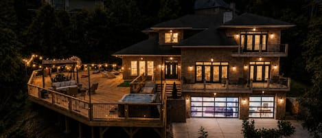 Una casa de dos pisos con terraza, mobiliario exterior y un jacuzzi.