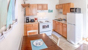 A compact kitchen with wooden cabinets, a white stove, a microwave, and a refrigerator.