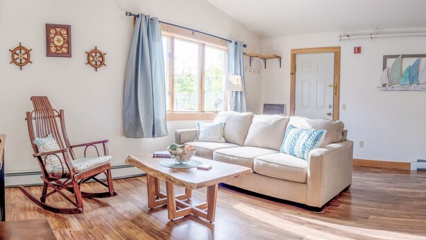 A cozy living room with a wooden rocking chair, a beige sofa, and a wooden coffee table.