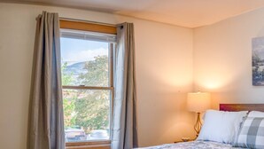 A bedroom with a bed, a nightstand, a lamp, and a window with curtains.