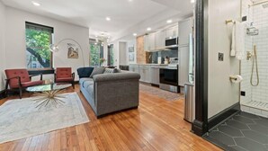 A modern living room with a sofa, armchairs, and a glass coffee table. - Sleeps 14 · Historic 4BR · Steps to Shaw Metro (Washington)
