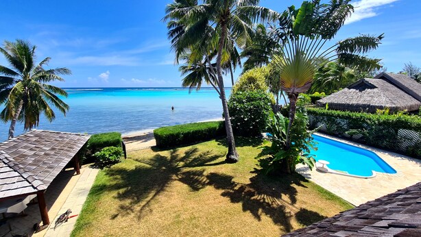 Un resort tropical con piscina, palmeras y vistas al océano.
